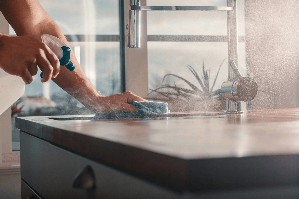 Cleaner spraying and wiping down a kitchen counter
