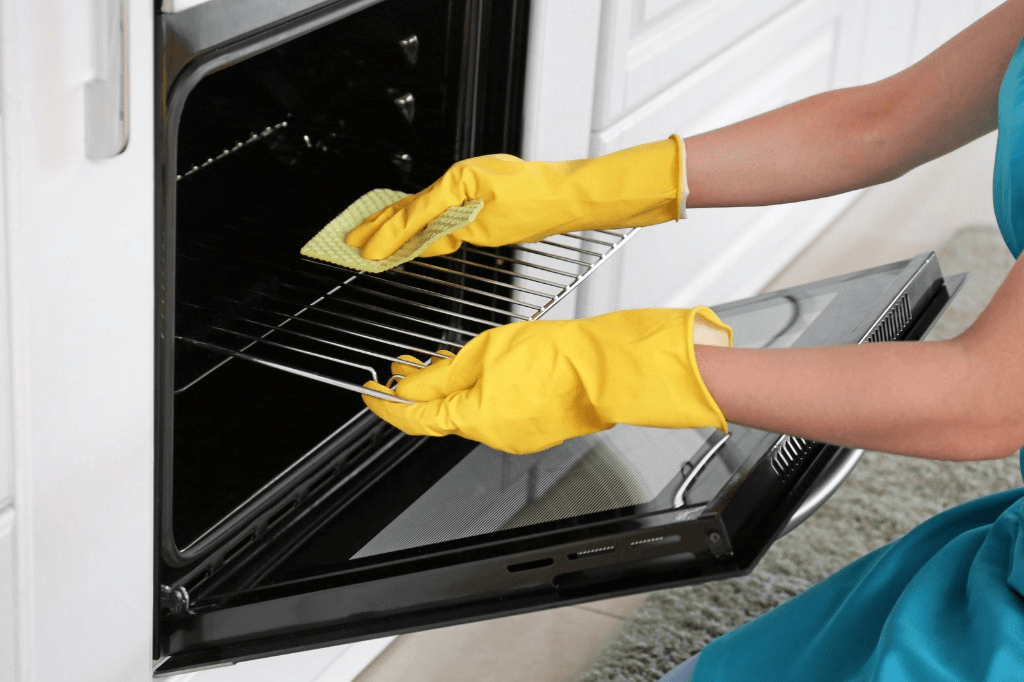 Gloved hands deep-cleaning the inside of an oven